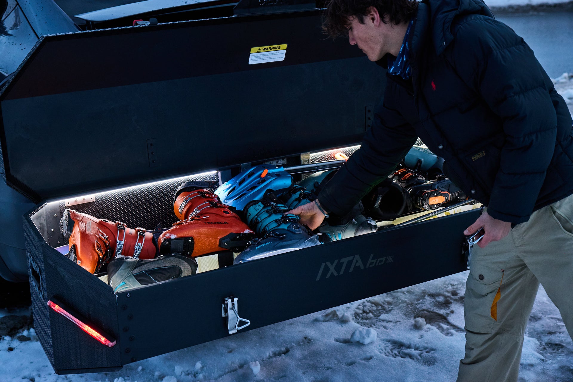 Geopende IXTAbox met skimateriaal en handschoenen in een besneeuwde winterse omgeving